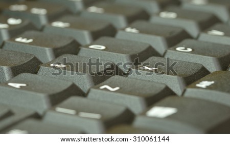 Computer keyboard. Close up of mostly blurred keys on an acute angle.