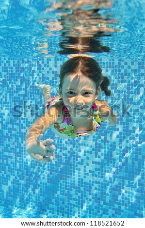 Happy smiling underwater child in swimming pool, beautiful healthy girl swims and having fun. Kids sport on family summer vacation. Active holiday. Vertical image
