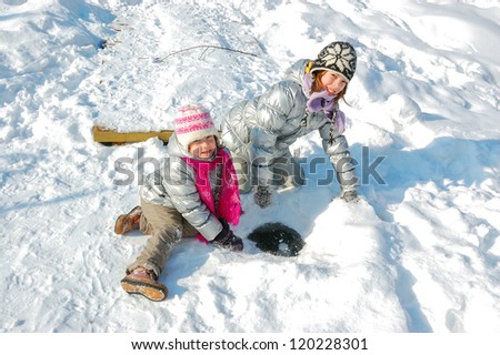 Kids having fun in winter outdoors, children playing with snow
