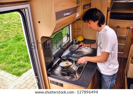 Family vacation, RV holiday trip, man cooking in camper. Motorhome interior