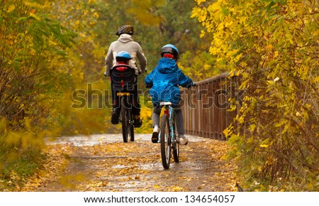 Family cycling outdoors, father and kids on bikes, golden autumn in park