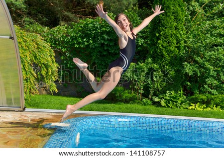 Happy girl jumps to swimming pool, active child having fun on vacation