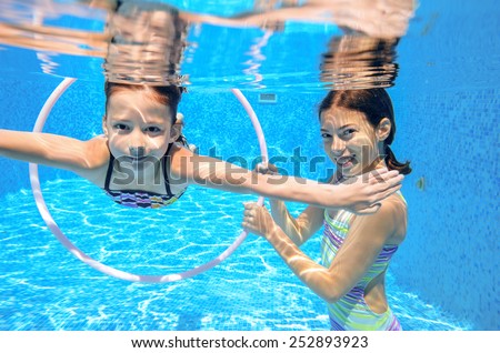 Kids swim in pool underwater, girls swimming, playing and having fun, children water sport