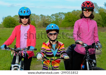 Happy mother and kids on bikes cycling outdoors, active family sport