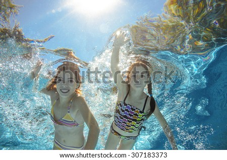 Children swim in pool underwater, happy active girls have fun in water, kids sport on family vacation