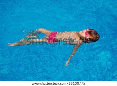 Happy little child swimming on her back in pool. Active girl swims and having fun. Child sport on summer vacation