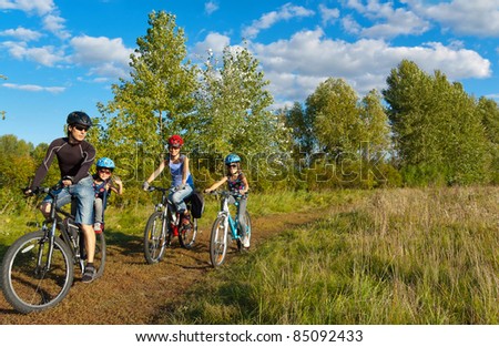 Family of four cycling outdoors. Happy parents with two kids on bikes