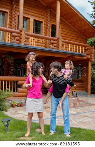 Happy smiling family near wooden house. Parents having fun with kids in garden. Vertical image