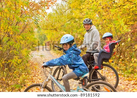 Family cycling outdoors, golden autumn in park