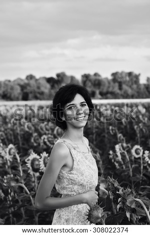 Happy young beautiful girl with a beautiful smile in a field of sunflowers. Smiling happy girl. Young woman resting on the nature.