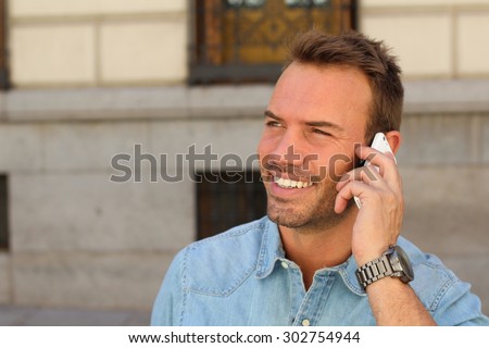 Hot young man calling with mobile phone . He is calling somebody by mobile telephone on the street