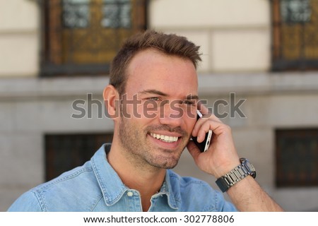 Happy young man calling with mobile phone . He is calling somebody by mobile telephone on the street
