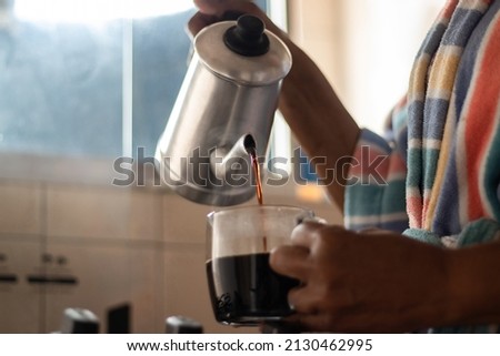 Brazilian black lady with colorful bathrobe and coffee pot in hands putting coffee in cup Imagine de stoc © 
