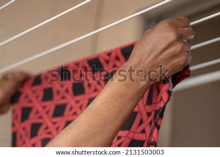 Hands of black brazilian lady extending her clothes with clothespin on fingers on clothesline in laundry Imagine de stoc © 