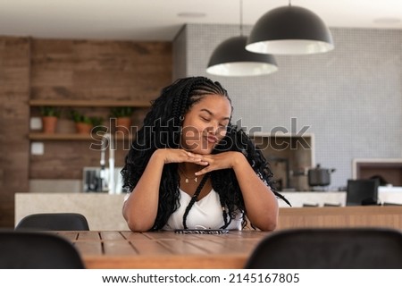 Young black brazilian woman with braided hair, necklace, earrings and white t-shirt in her kitchen Imagine de stoc © 