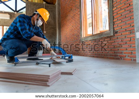 Asian artisan tiler at construction site, worker cuts a large slab of tile during the construction of a house, floor tile cutting equipment Photo stock © 