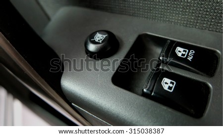 Car door interior arm rest with window control panel, door lock button, and mirror control.