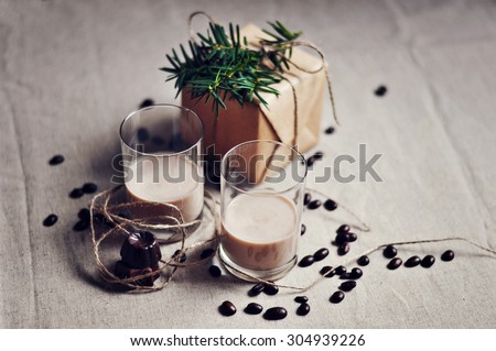 Shot glasses with homemade baileys liqueur, roasted coffee beans, chocolate sweets, and Christmas gift box, selective focus, toned image
