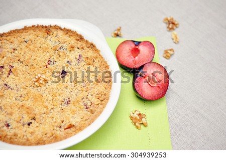 Plum tart, a pie with walnuts and juicy plums on a table, selective focus