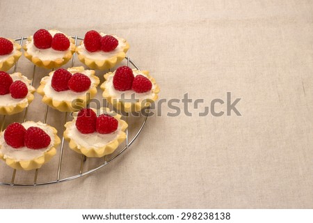 Homemade small cakes with cream cheese and fresh garden raspberries on a linen napkin