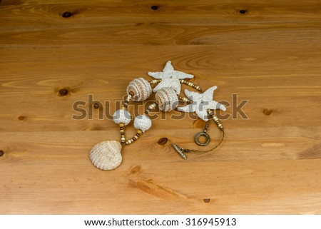 Crochet white-beige beads handmade pendant natural seashell and starfish knitted on a wooden table