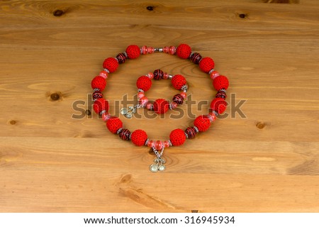 Crochet handmade red bracelet and necklace with pendants cherries on a wooden table