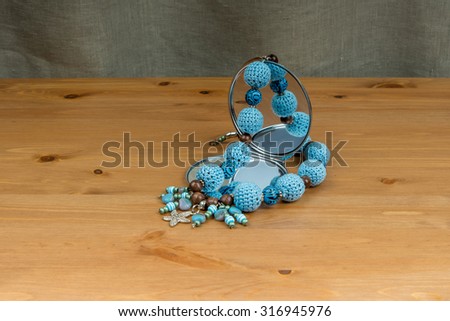 Crochet handmade blue beads with pendant starfish and a hand mirror on a wooden table