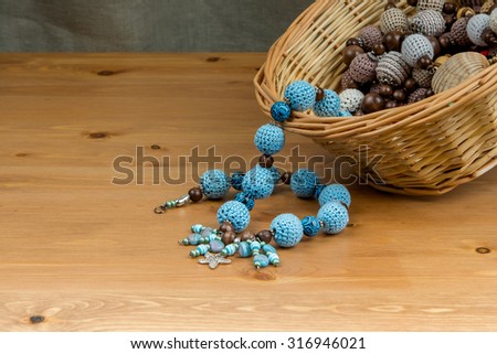 Crochet handmade blue beads with pendant starfish in a wicker basket on a wooden table