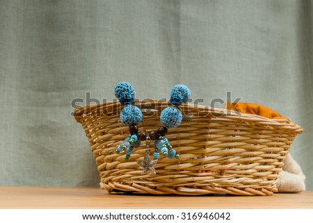 Knitted blue beads handmade pendant starfish in a wicker basket on a gray background