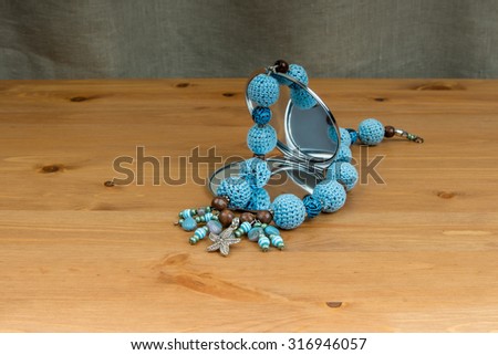 Handmade crochet blue beads with pendant starfish and a hand mirror on a wooden table