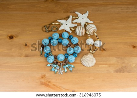 Crochet blue and beige beads handmade pendant starfish and natural sea shell in a wicker basket on a wooden table