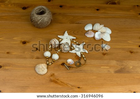 Crochet white-beige beads handmade pendant natural seashell and starfish knitted on a wooden table