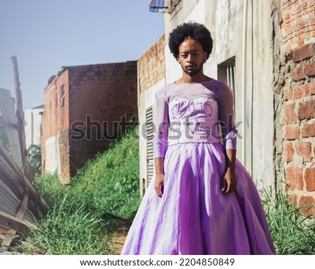 Young Brazilian man with an dressed in purple, moving gracefully against a gated backdrop. Imagine de stoc © 