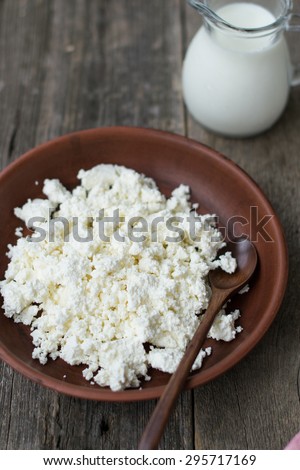 Cottage cheese and a jug of milk on a wooden background
