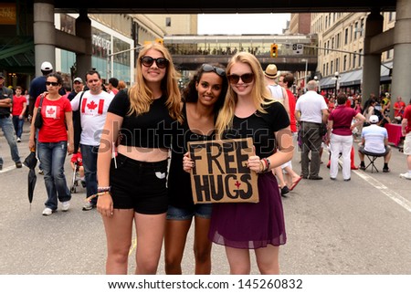 OTTAWA - JULY 1: Three young ladies offer free hugs to the massive crowd on Rideau Street in during the Canada Day, a national holiday, celebrations July 1, 2013 in the Canadian capital of Ottawa.