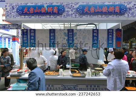 SHANGHAI, CHINA - NOV 13, 2014: Unidentified employees prepare food at a popular food kiosk in the busy Chenghuang Miao area in the Old City of Shanghai.