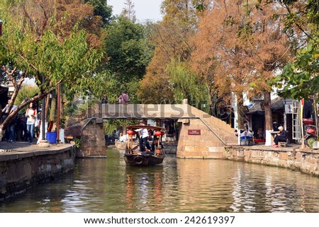 ZHUJIAJIAO, CHINA - NOV 10, 2014: Sightseeing boat take tourists on tour of the ancient water town of Zhujiajiao located in the Qingpu District of Shanghai. The streets are filled with small shops.