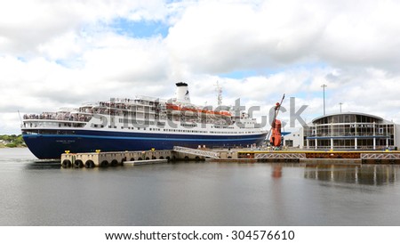 SYDNEY, NOVA SCOTIA, CANADA - AUG 8, 2015:  The MS Marco Polo pulling out of dock near the Joan Harris Cruise Pavilion, and the world\'s largest fiddle in Sydney, Cape Breton, Nova Scotia.