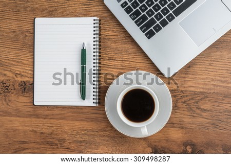 Laptop, notebook and pen with coffee cup on work desk