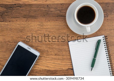 Notepad, notebook and pen with a cup of coffee on work desk