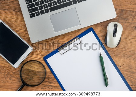 laptop, Mouse, magnifying paper and pen with Tablet on the  table