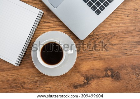 Laptop, notebook and pen with coffee cup on work desk