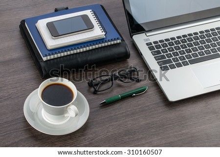Laptop Smart Phone notebook and pen with a cup of coffee on the desk