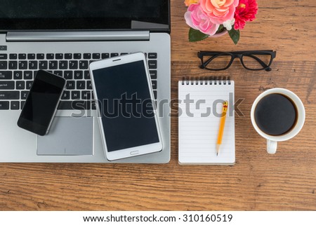 Laptop Mobile Phone and Tablet with notebook and a cup of coffee on the desk