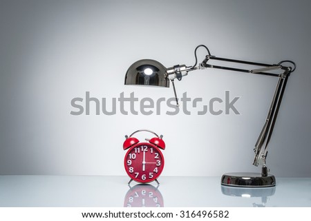 lighting up red alarm clock with desk lamp on round studio lighting