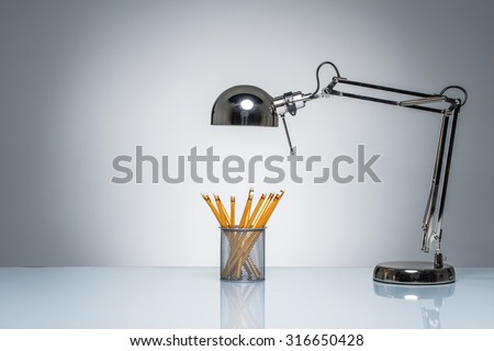 lighting up orange pencil holder stationery with desk lamp on round studio lighting