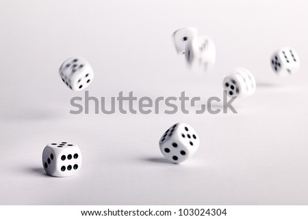 Multiple thrown dice bouncing across a white surface with movement and motion blur