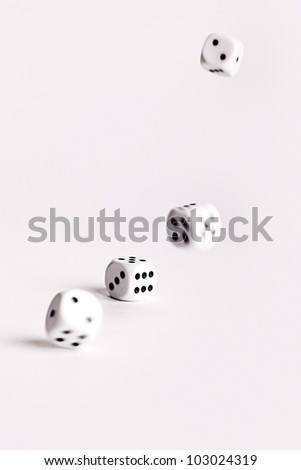 Multiple thrown dice bouncing across a white surface with movement and motion blur