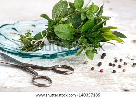 Thyme, Sage and Rosemary with Laurel bundled with cotton string and old rusty scissor on wooden board