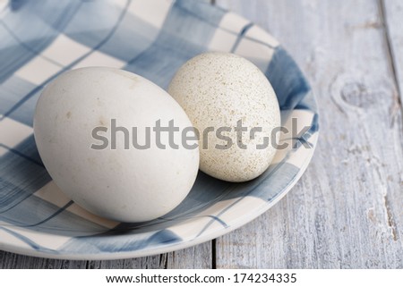 Egg of Goose And Duck on white and blue plate on wooden board